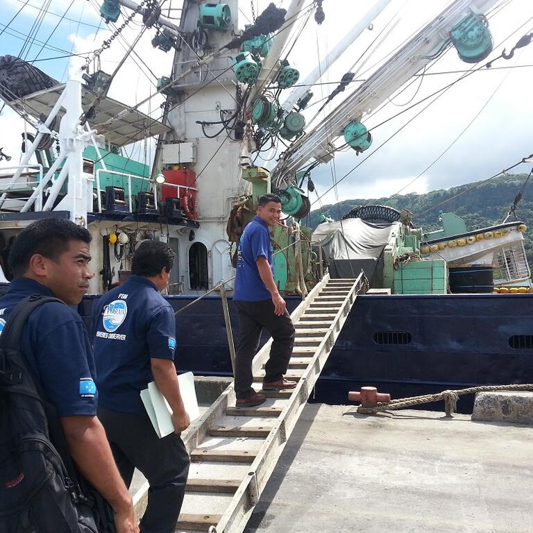 Fisheries observers carrying documents boarding a vessel 