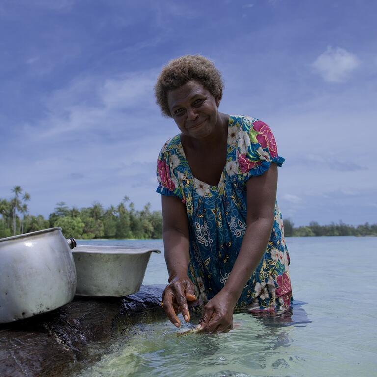 Woman in sea water washing fish