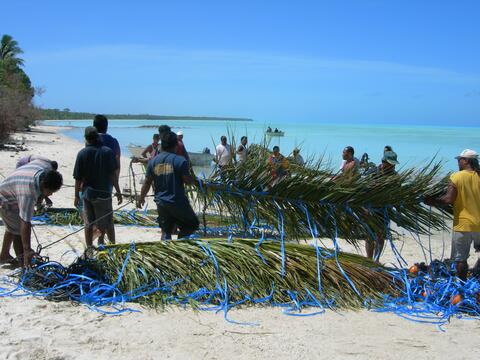 People making a fish aggregating device on a beach