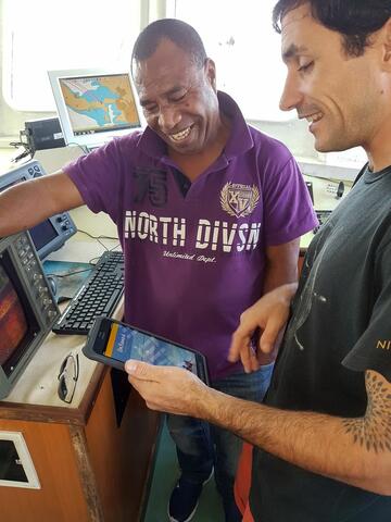 Two men using OnBoard on a tablet on a longline vessel.